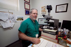 Physician at desk with microscope.