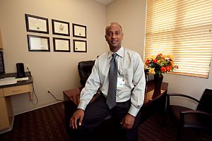 Physician sitting at edge of desk